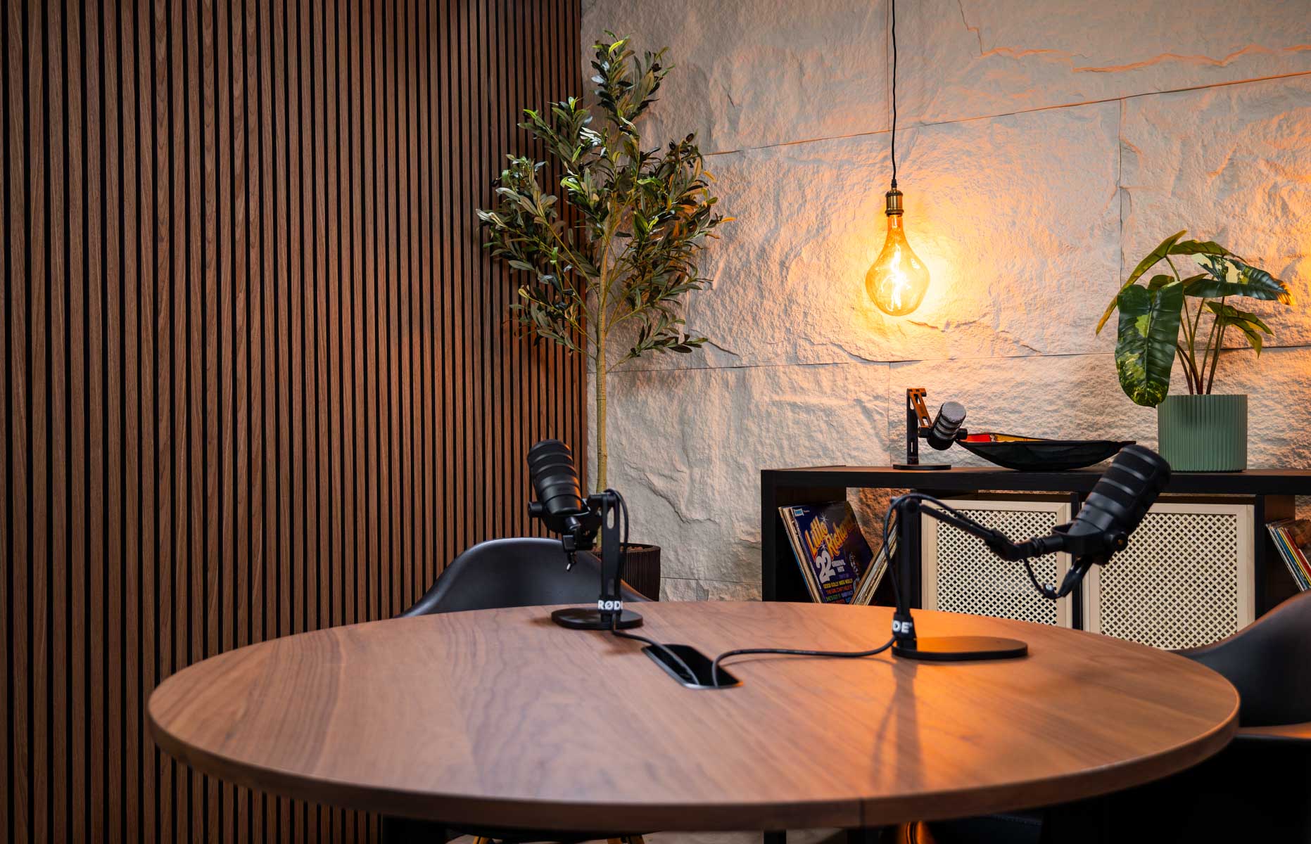 Professionele videopodcaststudio van Mendus Productions met RØDE-microfoons, houten lattenwand en warme belichting