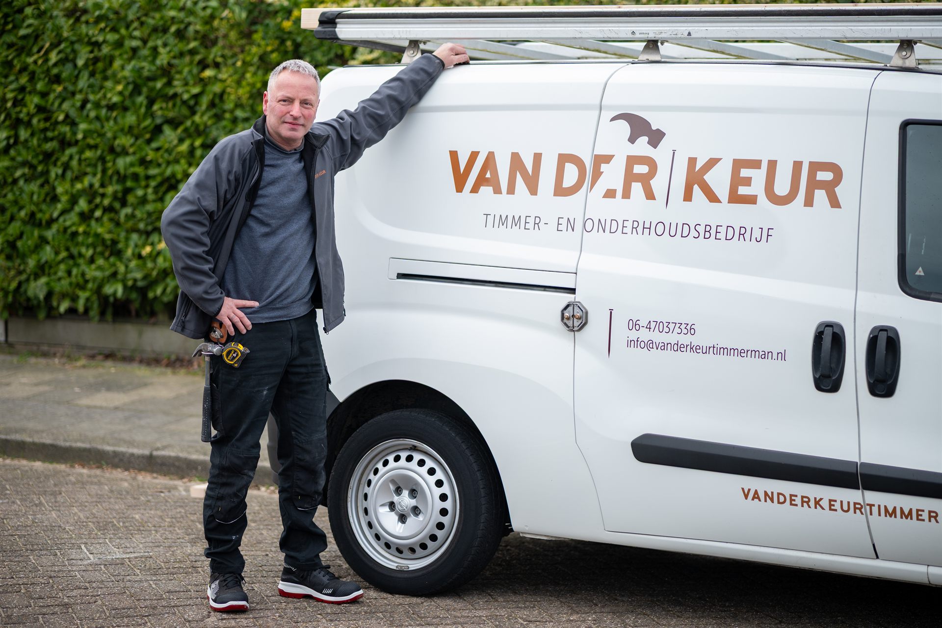 timmerman van Van der Keur bij zijn bedrijfswagen met gereedschap.