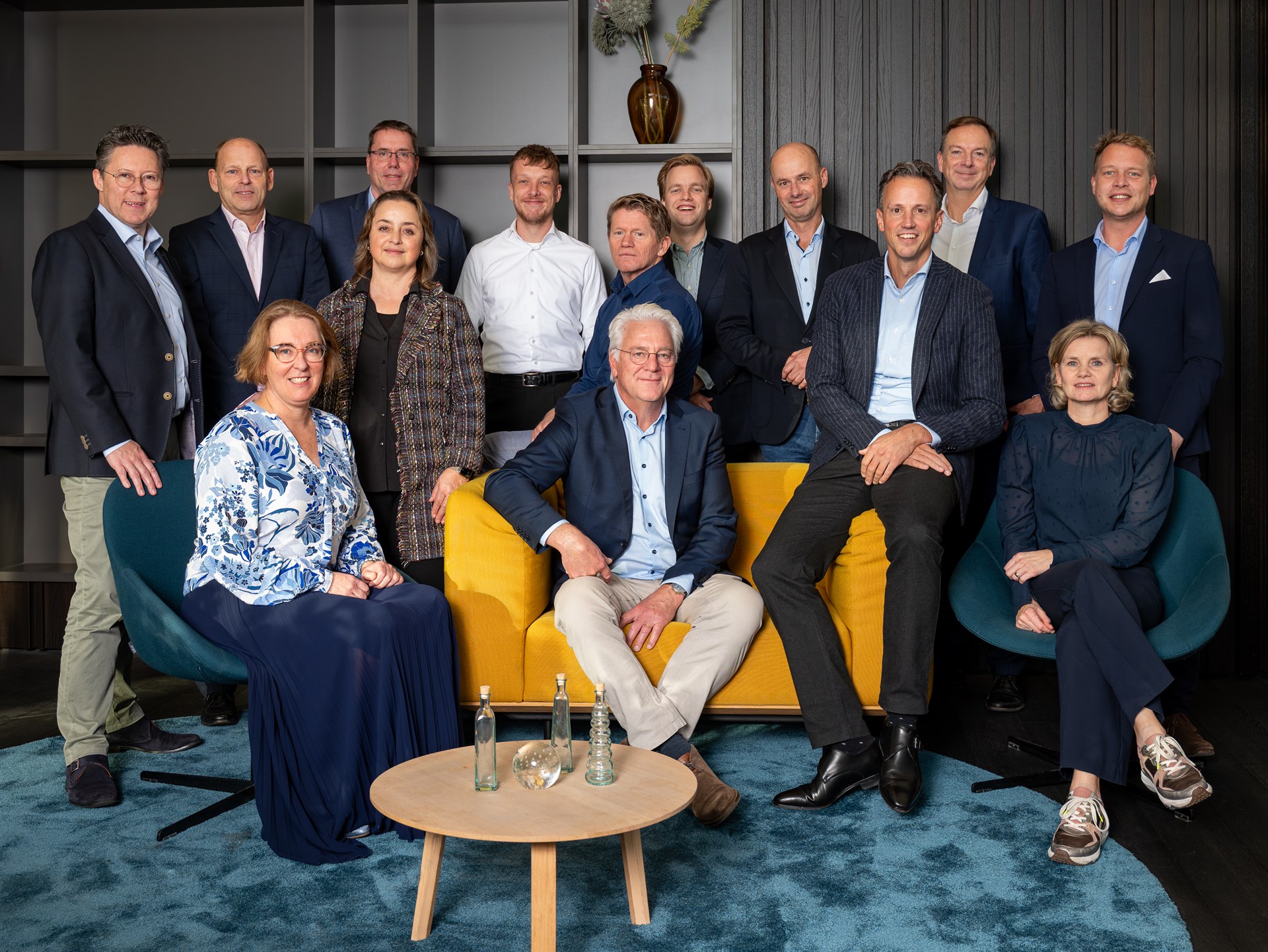 Zakelijke groepsfoto van een managementteam in een moderne kantooromgeving met gele bank.