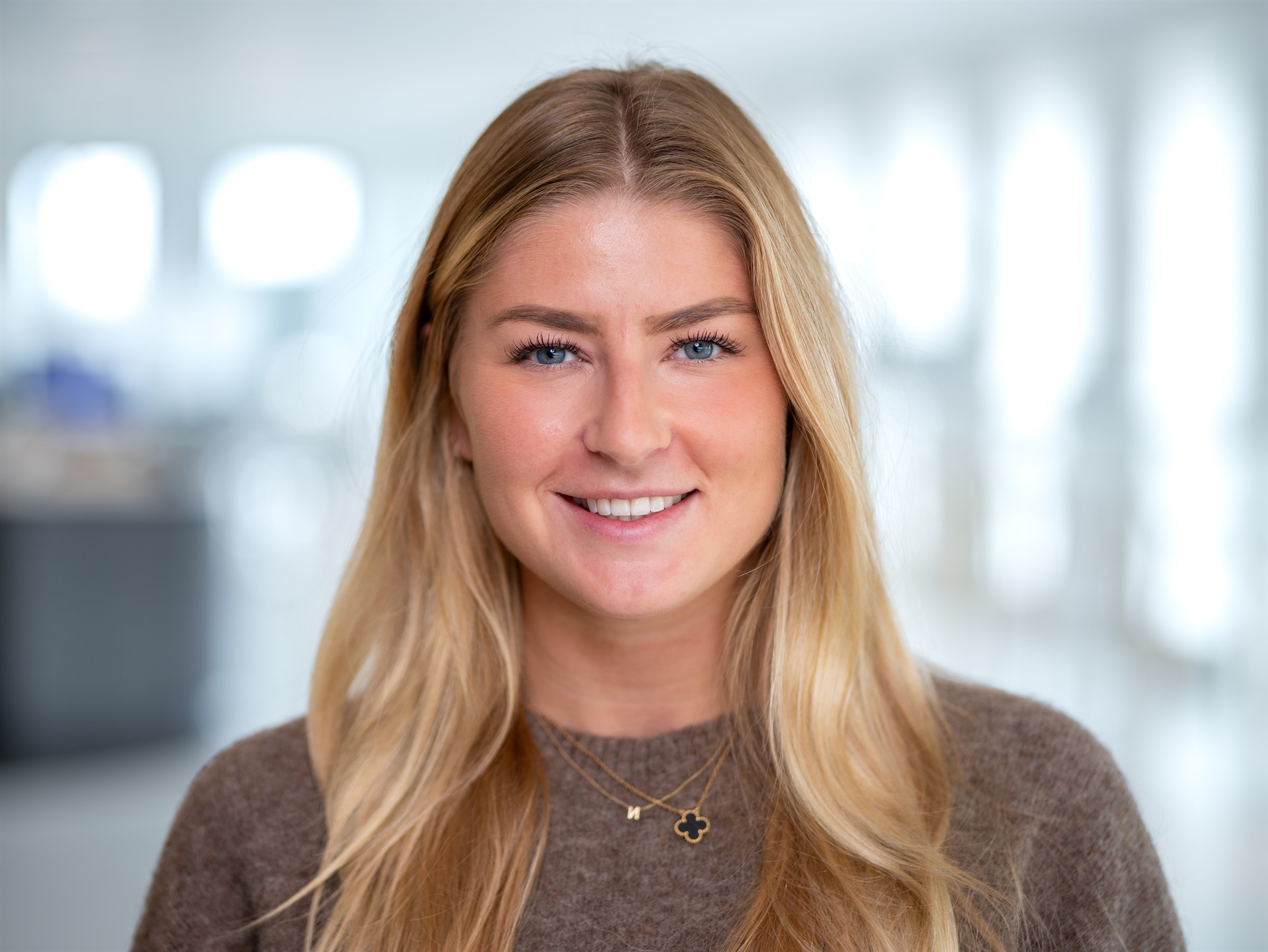 Zakelijk portret van een glimlachende vrouwelijke professional in een lichte kantooromgeving.
