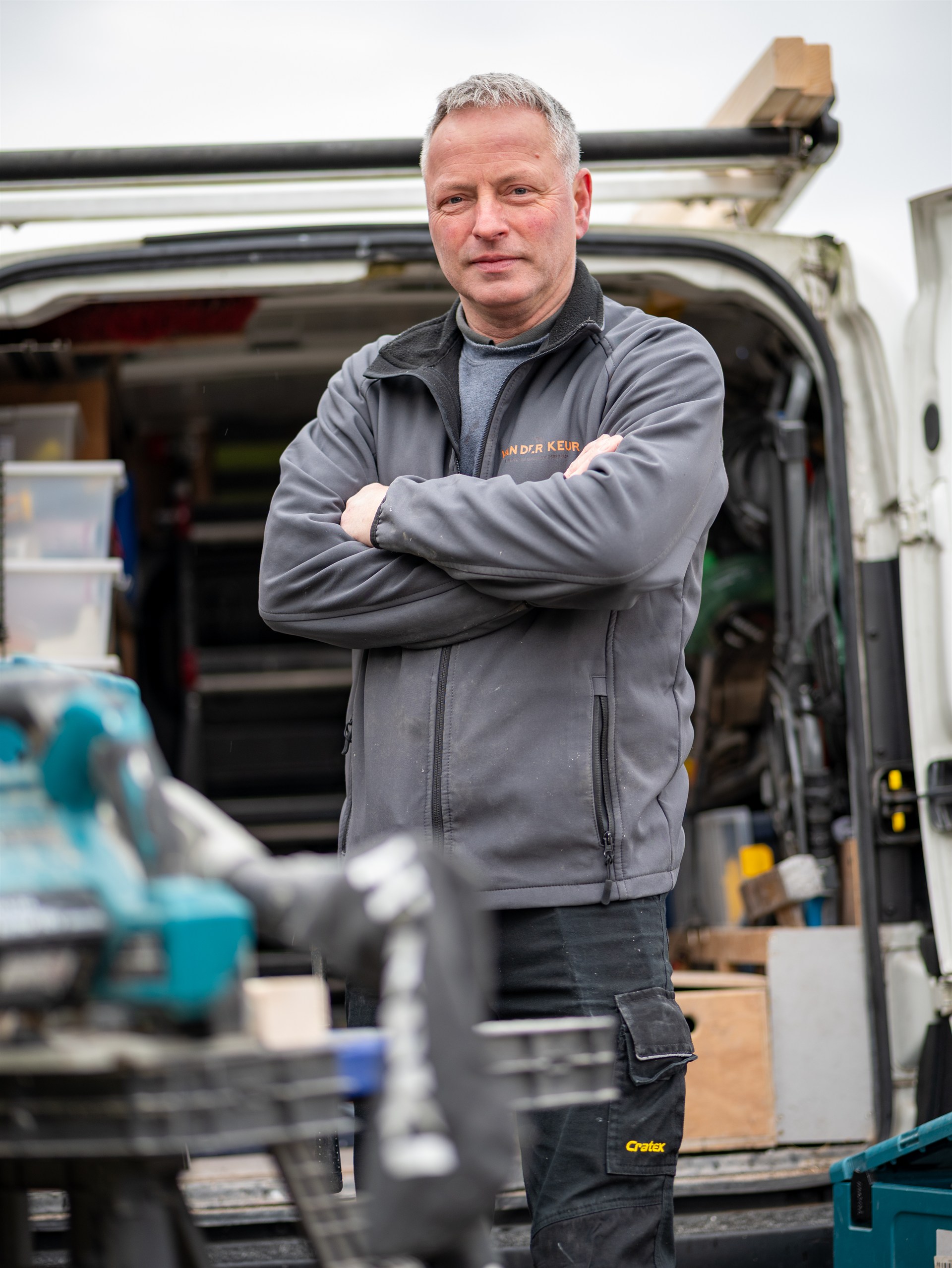 timmerman van Van der Keur bij zijn bedrijfswagen met gereedschap.