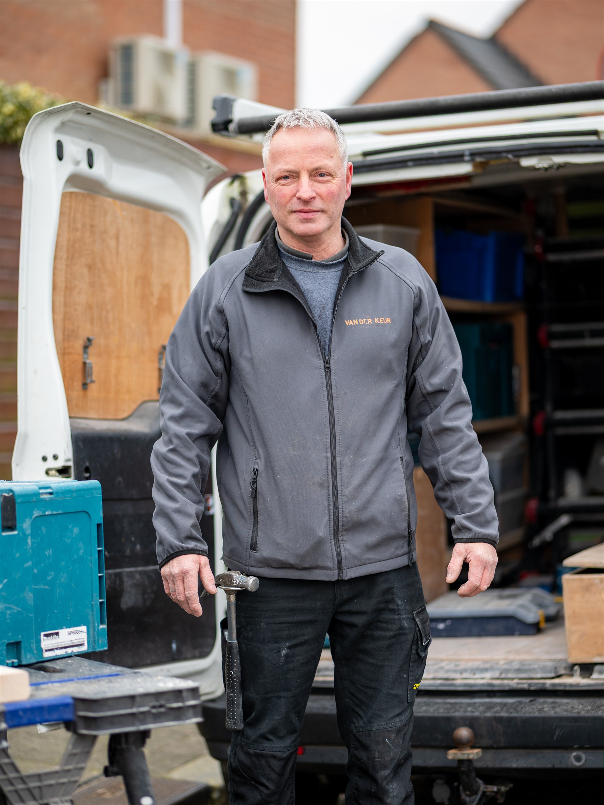 timmerman van Van der Keur bij zijn bedrijfswagen met gereedschap.